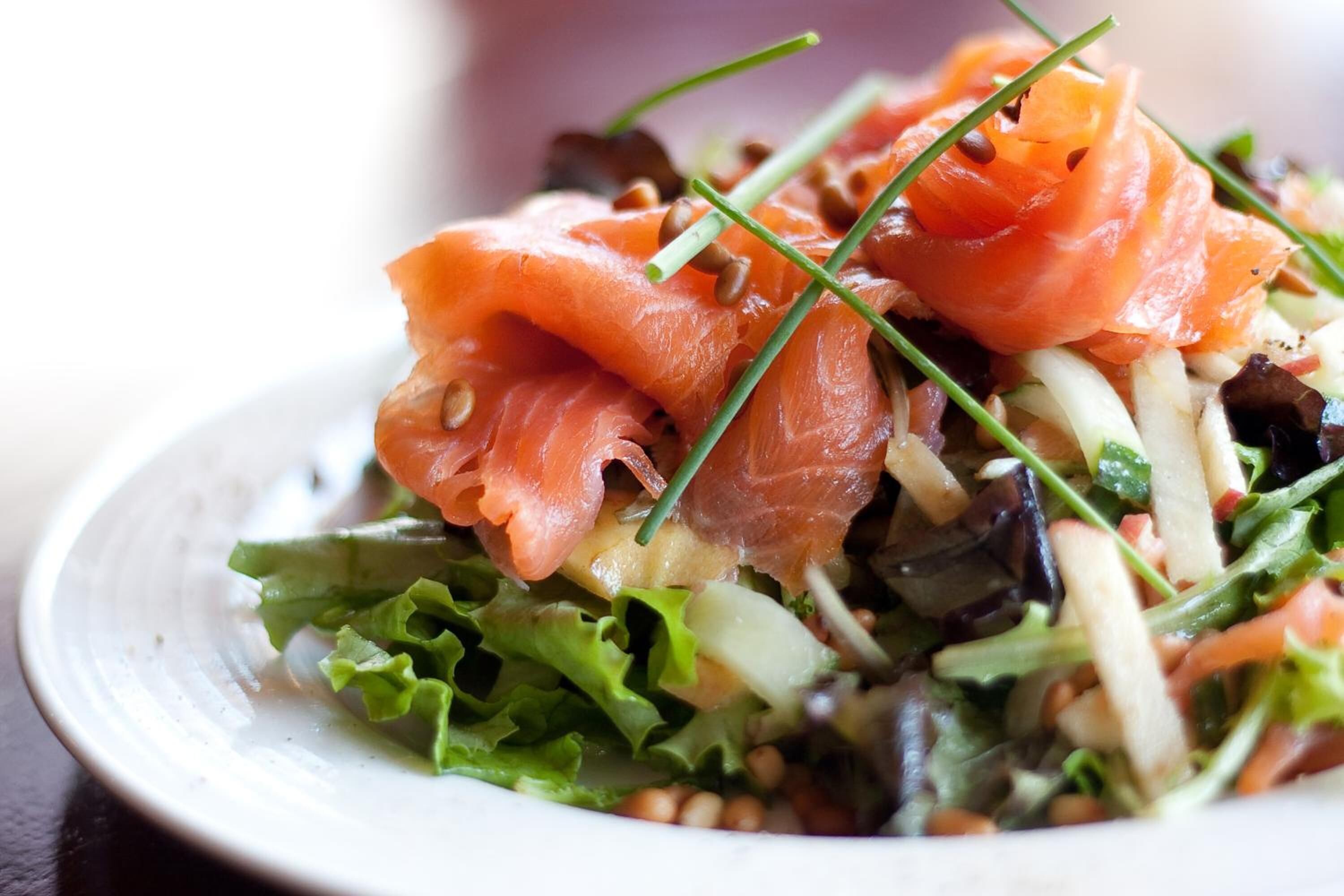 A plate of food with salmon, greens, and other vegetables.
