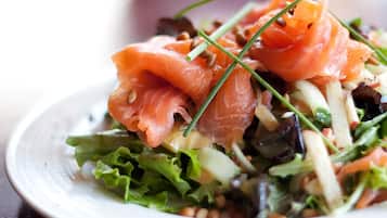 A plate of food with salmon, greens, and other vegetables.