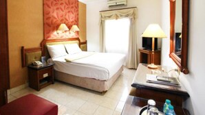 Une chambre d’hôtel avec un lit, une table de chevet, une lampe et un miroir.