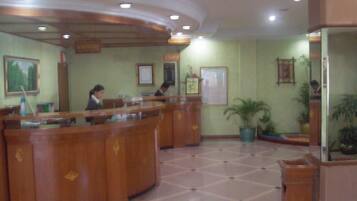 A reception area with a curved wooden counter, several framed certificates or awards on the wall, and potted plants.