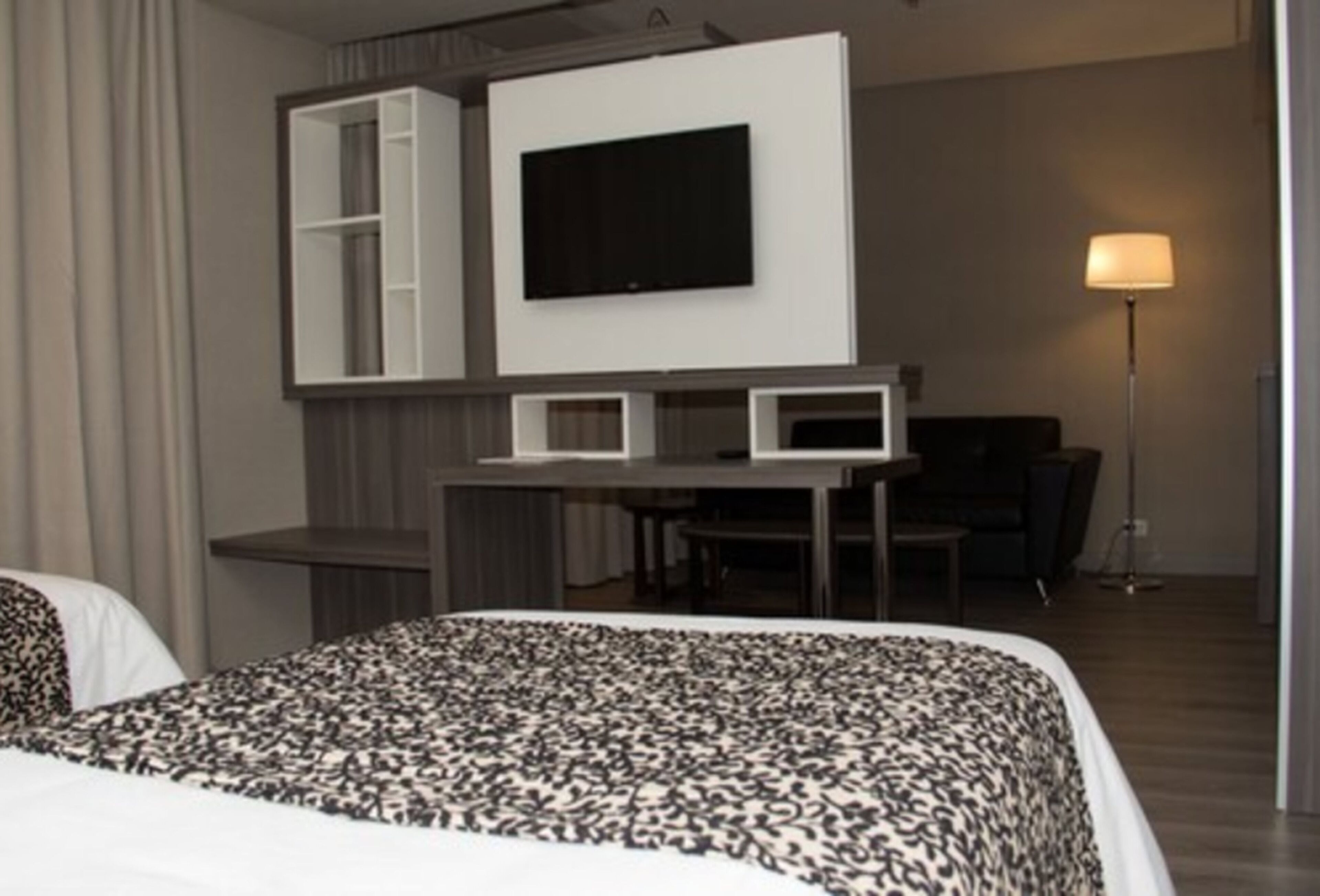Habitación de hotel con cama, escritorio, televisor de pantalla plana, silla y lámpara.