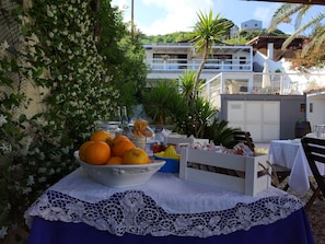 A table with a bowl of oranges and a basket of bread, surrounded by white lace tablecloths and a white fence. - La Casa a Mare (Messina)