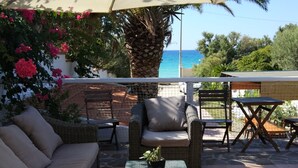 A patio area with wicker furniture, a glass table, and a view of the sea. - La Casa a Mare (Messina)