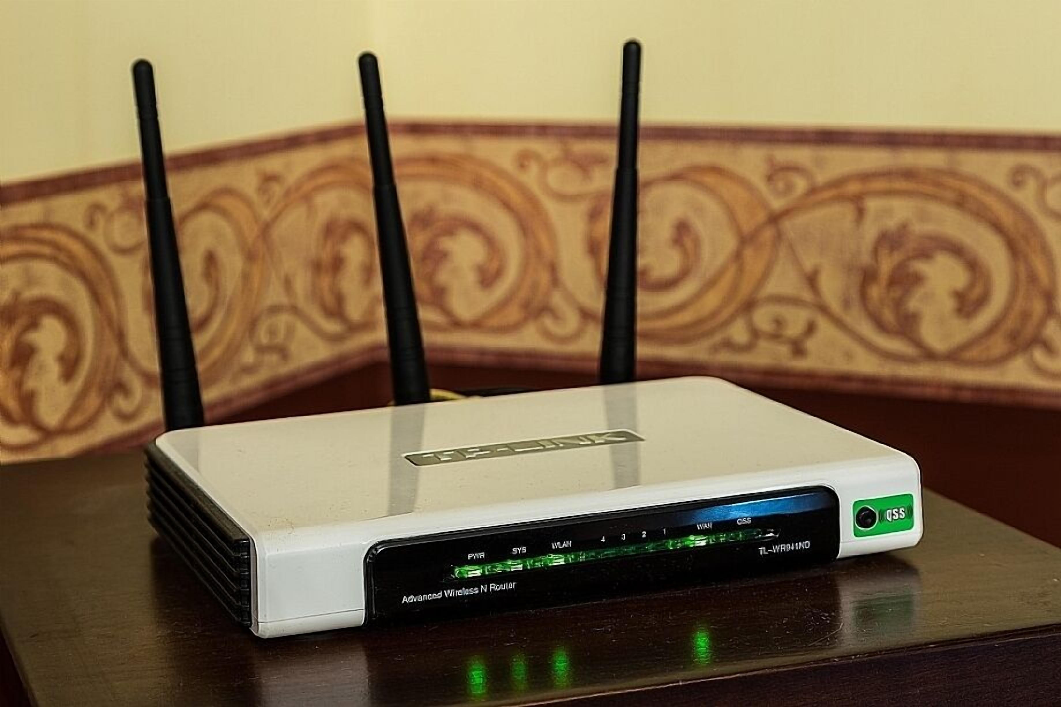A white router with four antennas on a wooden table.