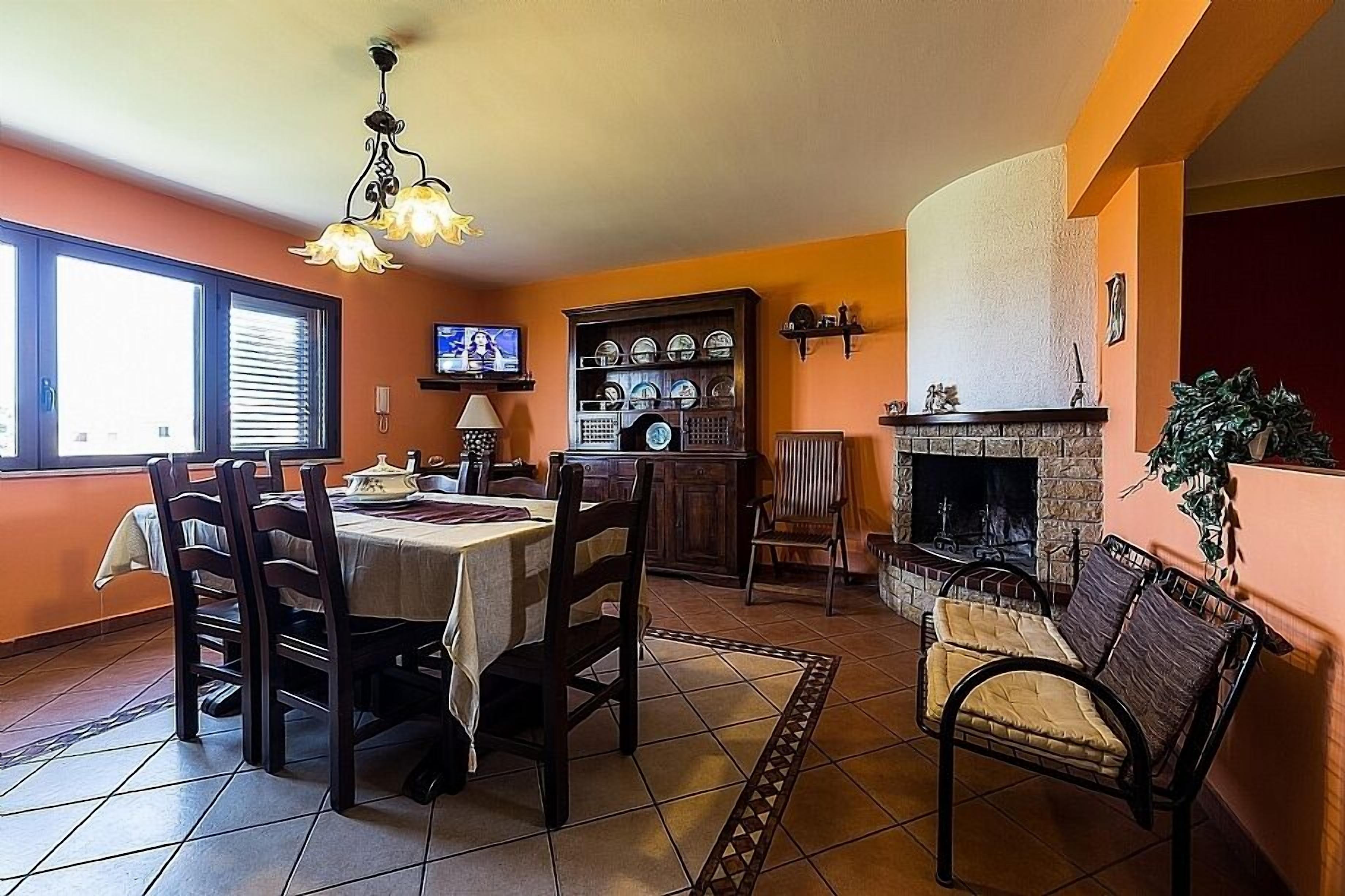 A dining area with a table set for four, a fireplace, and a television on the wall.