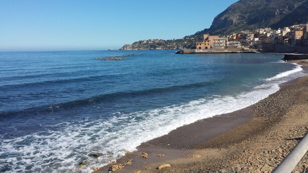 A coastal town with a beach, rocky shoreline, and buildings on a hillside. - Bed & Breakfast Marina D'Aspra (Bagheria)