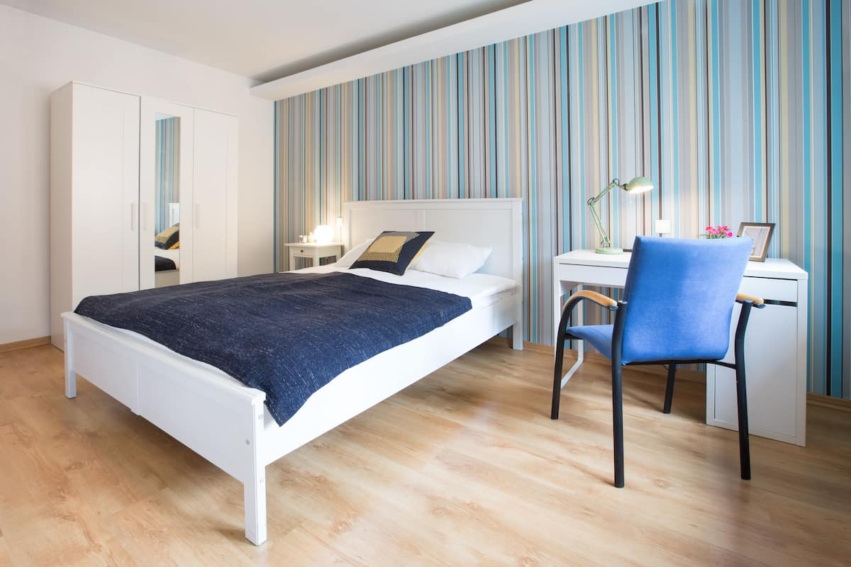Ein modernes Schlafzimmer mit Bett, Schreibtisch, Stuhl und Kleiderschrank.