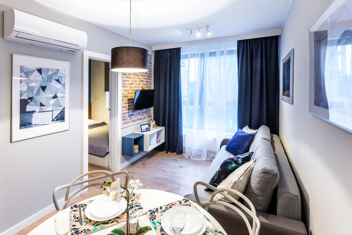 Ein modernes Wohnzimmer mit Essbereich, einer Couch, einem Fernseher und einer Wand mit Backsteinverkleidung.