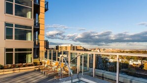 A rooftop pool with lounge chairs and a glass balustrade overlooking a cityscape. - Bridgestreet the View at Liberty Center (Arlington)