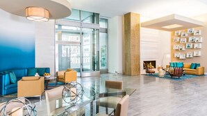 A modern lobby with a glass coffee table, sofas, and a fireplace. - Bridgestreet the View at Liberty Center (Arlington)
