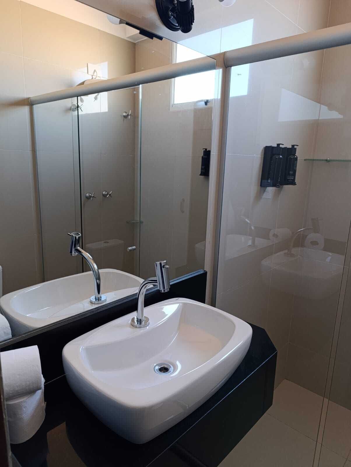 A modern bathroom with two sinks, a glass shower enclosure, and a large mirror.