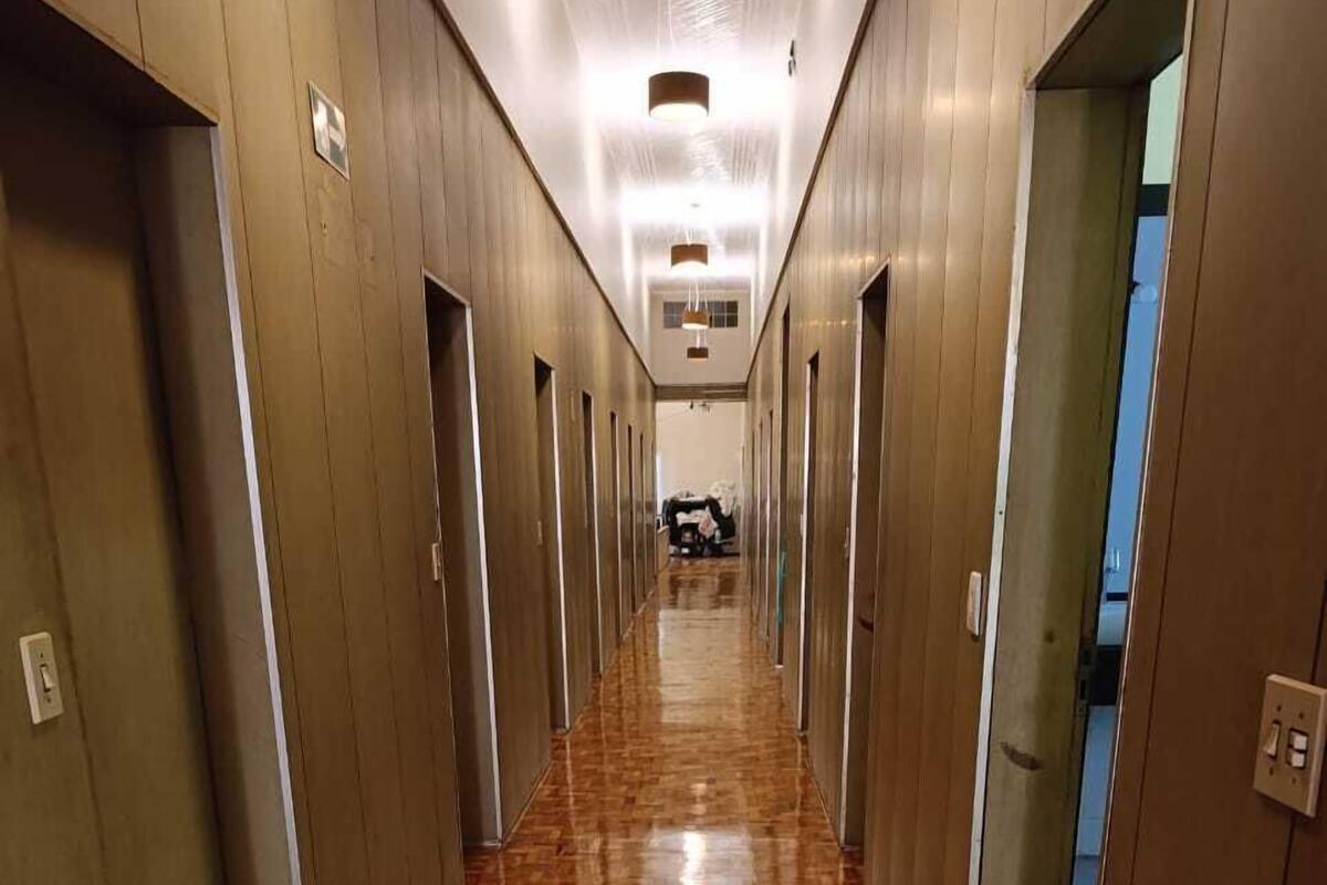 Un largo pasillo con suelo de madera pulida y puertas a ambos lados, que conduce a habitaciones individuales.