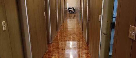 Un largo pasillo con suelo de madera pulida y puertas a ambos lados, que conduce a habitaciones individuales.
