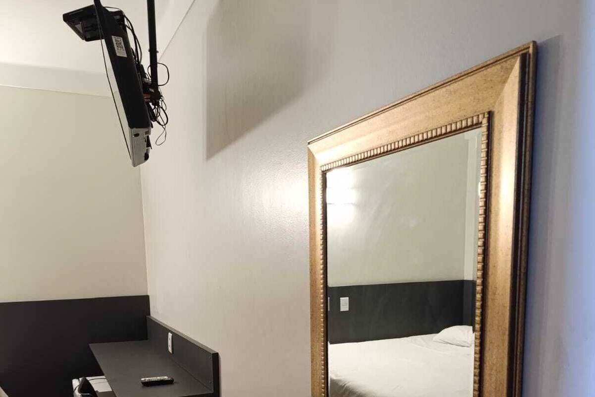 Una habitación con una cama, un escritorio y un espejo grande en la pared.