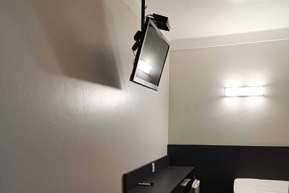 Una habitación pequeña y tenuemente iluminada con una mesa, una silla y una cama.