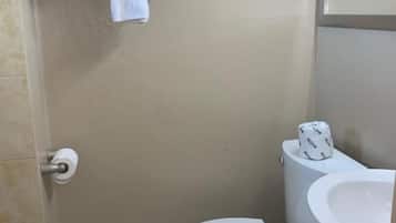 Une salle de bain équipée de toilettes, d’un lavabo et d’un porte-serviettes.