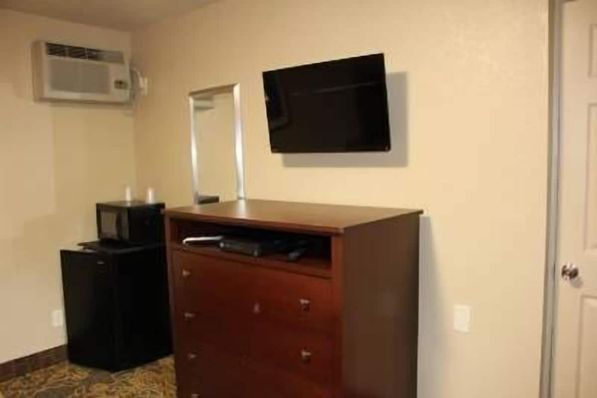 Een kamer met een houten dressoir, een zwarte kast en een wandgemonteerde flatscreen-televisie.