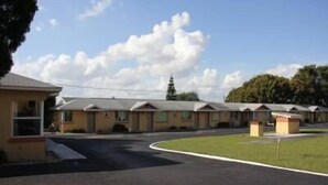 A row of motel-style buildings with a parking lot in front.