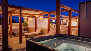Uma área de spa no terraço com hidromassagem, espreguiçadeiras e lanternas penduradas.
