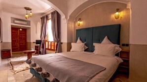 Quarto espaçoso com cama grande, teto em arco e vista para uma porta de madeira.