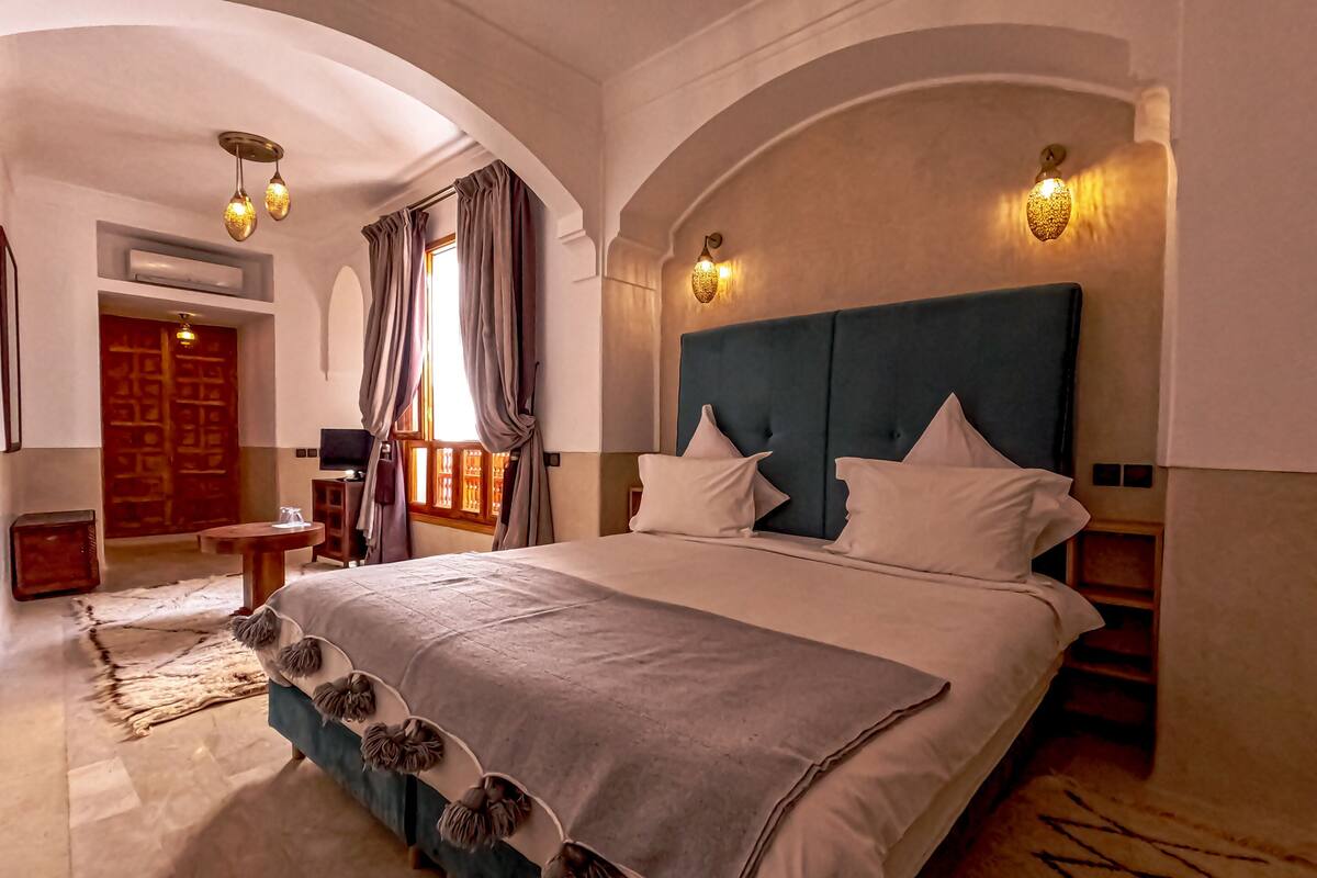 A spacious bedroom with a large bed, arched ceiling, and a view of a wooden door.