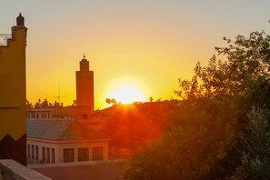 Vista do pôr do sol com uma torre imponente e edifícios ao primeiro plano.