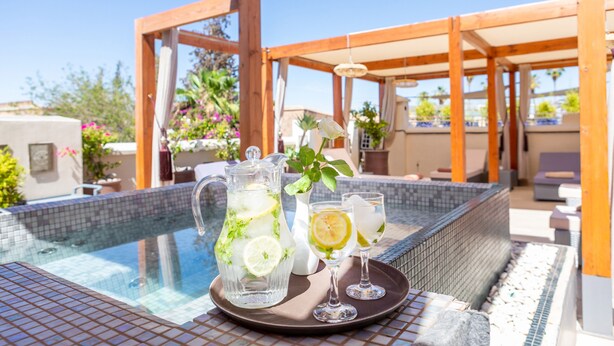 Cenário à beira da piscina com um jarro de vidro transparente, dois copos e uma bandeja.