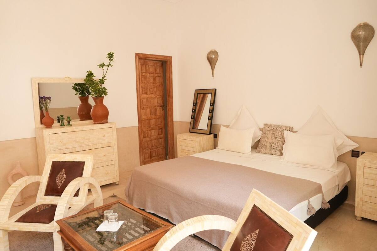 A bedroom with a bed, two nightstands, a dresser, a mirror, and a small table with a glass top.
