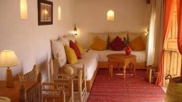 A cozy living room with a sofa, wooden chairs, a small table, and a red rug.
