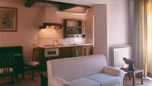 Ein Wohnzimmer mit einer Couch, einem kleinen Tisch mit einer Vase und einer Küchenzeile im Hintergrund.