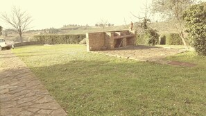 A stone structure with a stone pathway leading to it, surrounded by grass and trees.