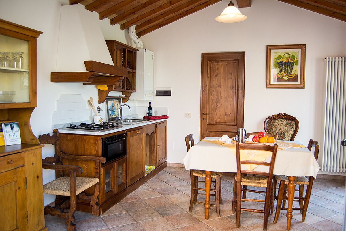 A rustic kitchen with wooden cabinets, a gas stove, and a dining table set for four.