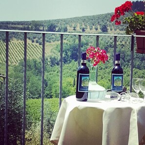 Ein Tisch im Freien mit zwei Weinflaschen und einem Blumenstrauß, mit Blick auf einen Weinberg.