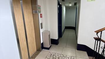 A hallway with a patterned floor, a trash bin, and a sign indicating an exit.