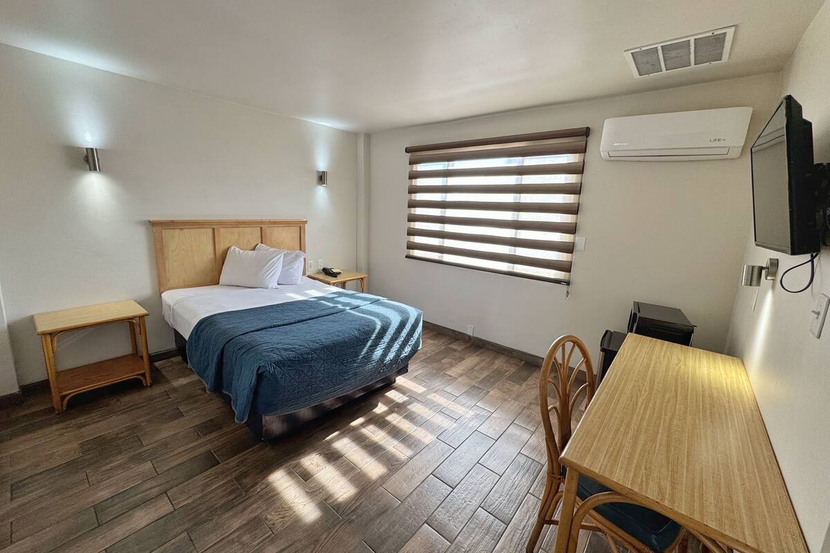 A bedroom with a bed, bedside tables, a desk, and a chair.