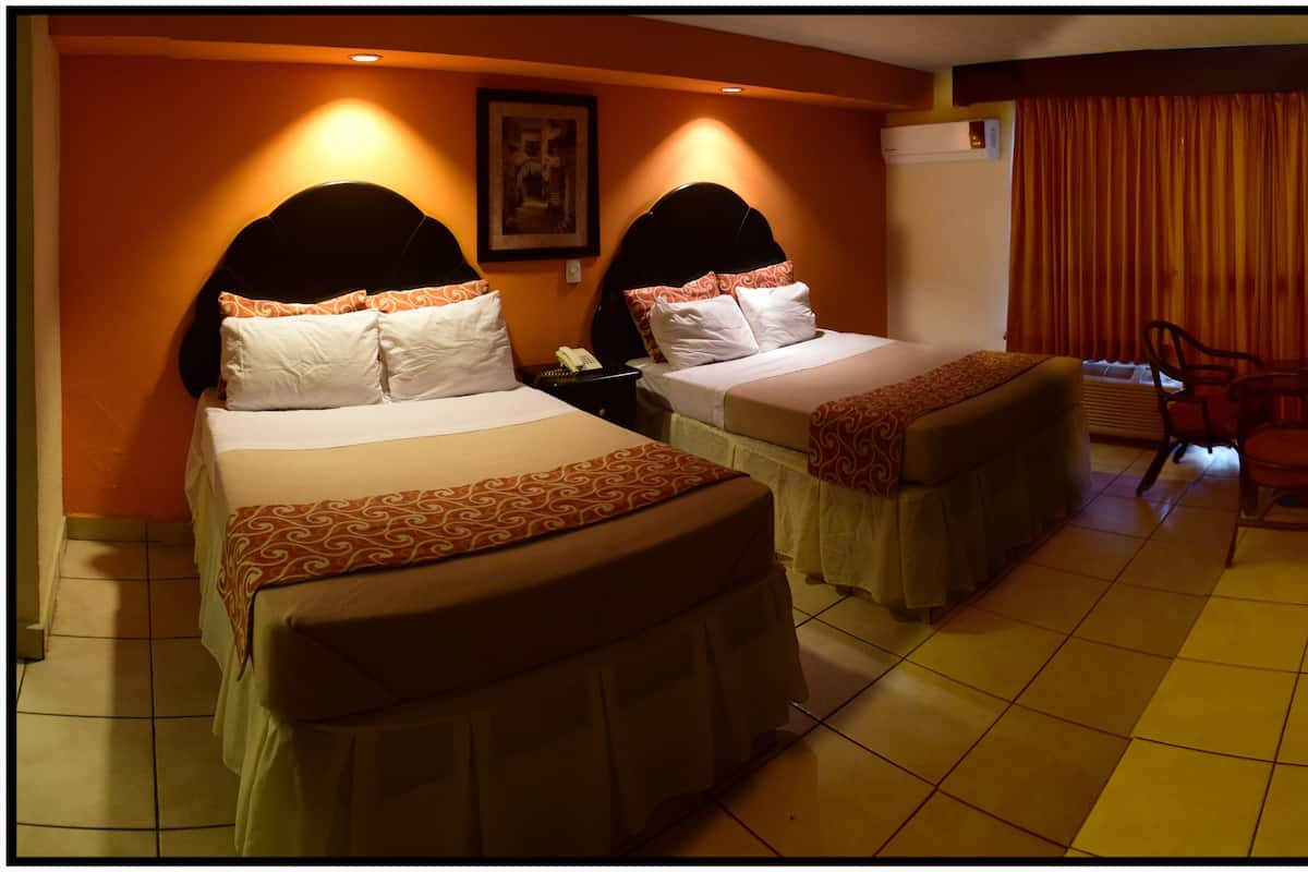 A hotel room with two beds, a desk, a chair, and a TV.