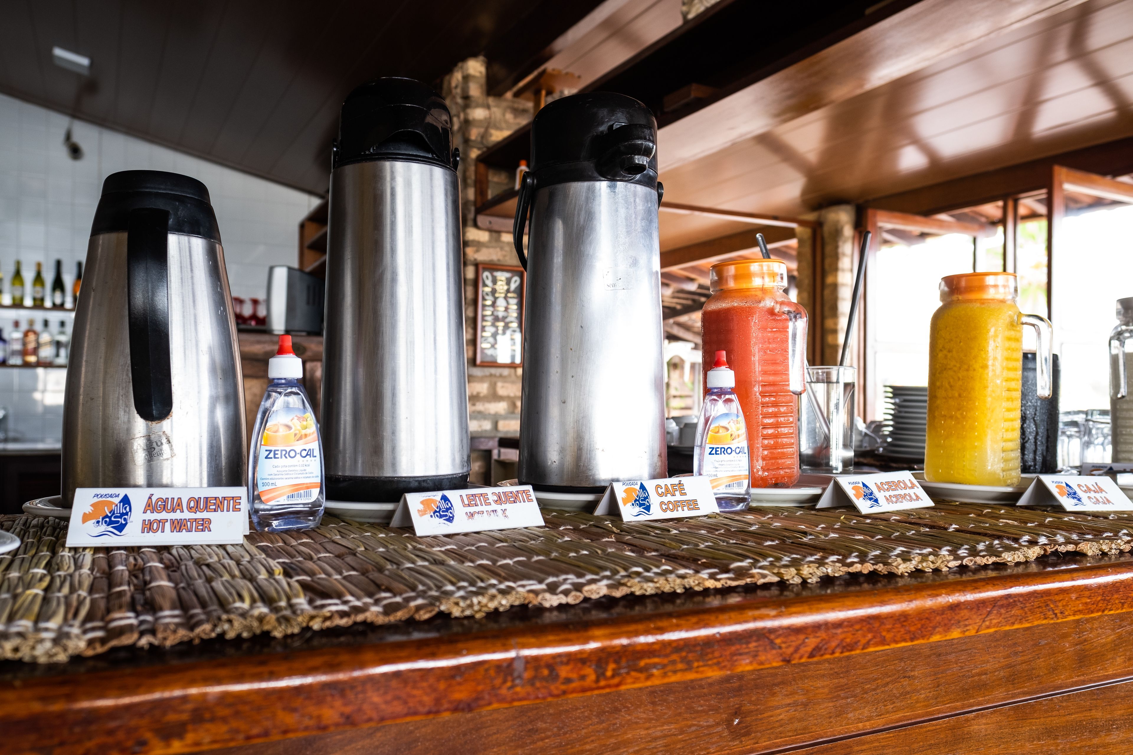 A bar area with various beverage dispensers and labels for hot water, milk, coffee, and juice.