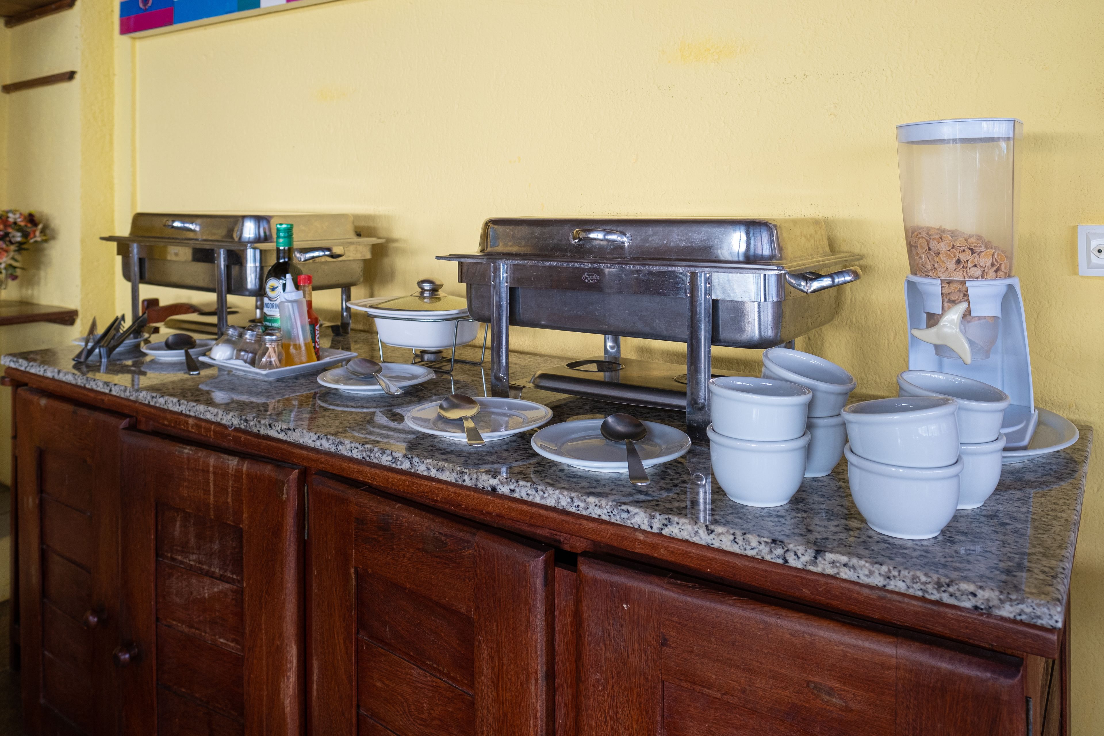 Una barra de desayuno con diferentes recipientes de comida y utensilios para servir sobre una encimera de granito.