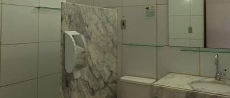 Ein Badezimmer mit Toilette, Dusche, Waschbecken und Spiegel.