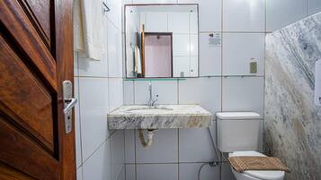 A bathroom with a marble sink, a toilet, and a wooden door.