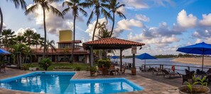 Una piscina al aire libre, sombrillas, sillones reclinables de piscina