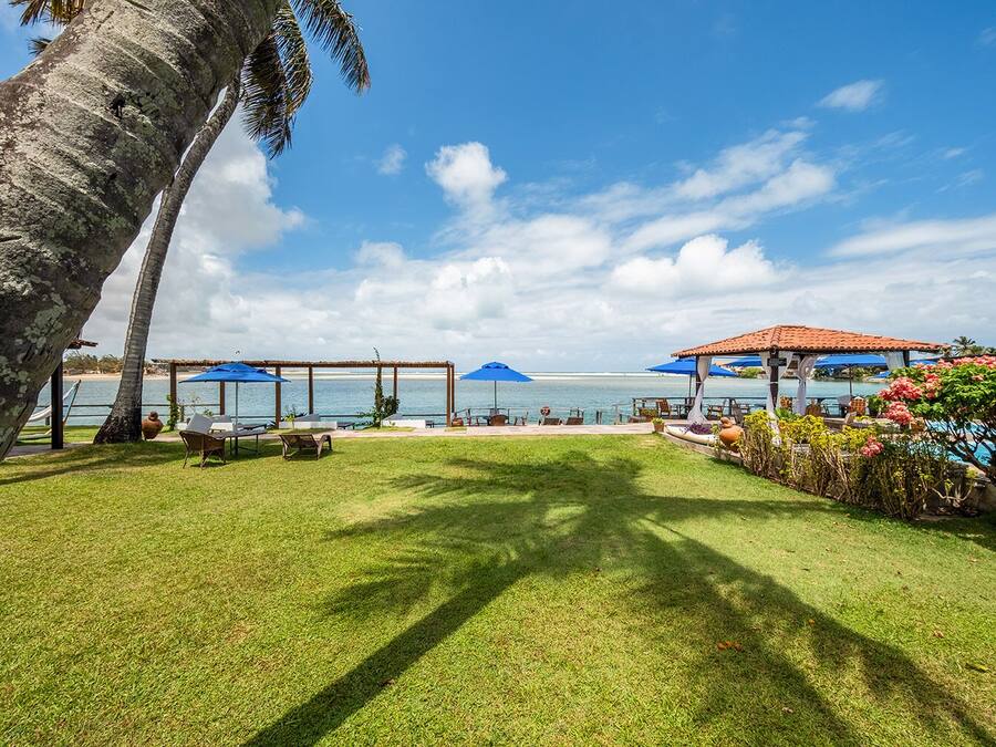A well-maintained outdoor area with a grassy lawn, seating arrangements, and a view of the sea.