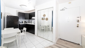 A compact kitchen with a white table and chairs, a black refrigerator, and a microwave. - Art Deco Ocean Walk Apartments (Miami Beach)