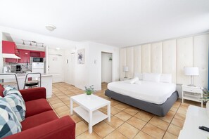 Ein Hotelzimmer mit einem Bett, einem roten Sofa, einem weißen Couchtisch, einer Küchenzeile und einem Badezimmer.