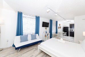 Ein modernes Hotelzimmer mit Bett, einer Couch, einem Schreibtisch und einer Küchenzeile.