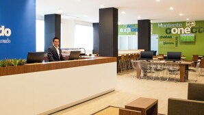 Un espace d’accueil moderne comprenant un comptoir d’accueil, un bureau de réception et un espace détente avec des tables et des chaises.