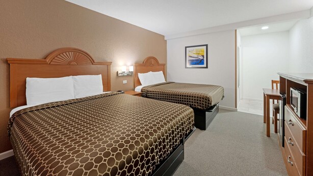 A hotel room with two beds, a desk, a chair, and a television. - Rodeway Inn Terre Haute near University (Terre Haute)
