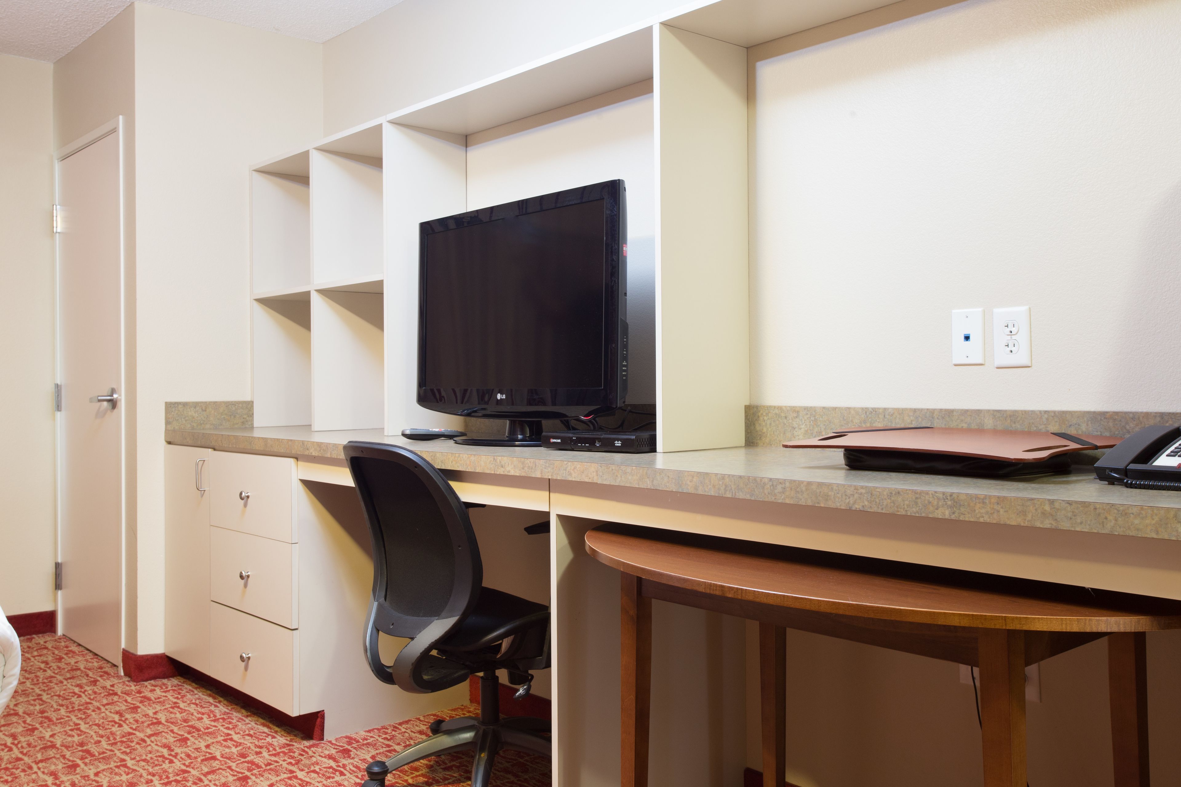 Una habitación con un escritorio, una computadora, una silla y una mesita.