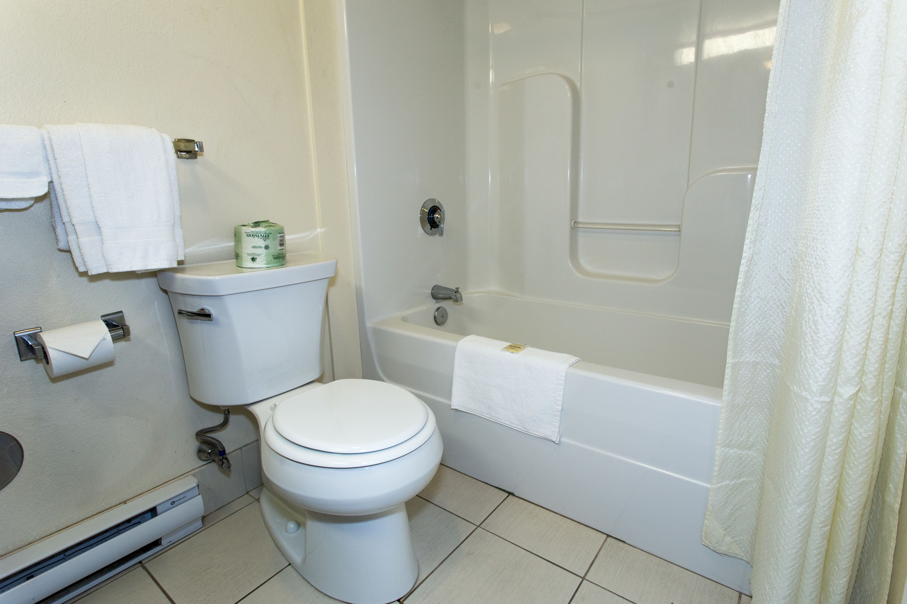 A bathroom with a toilet, a bathtub, and a shower curtain.