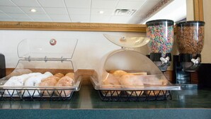 Un buffet de petit-déjeuner avec des présentoirs transparents remplis de viennoiseries et de céréales.